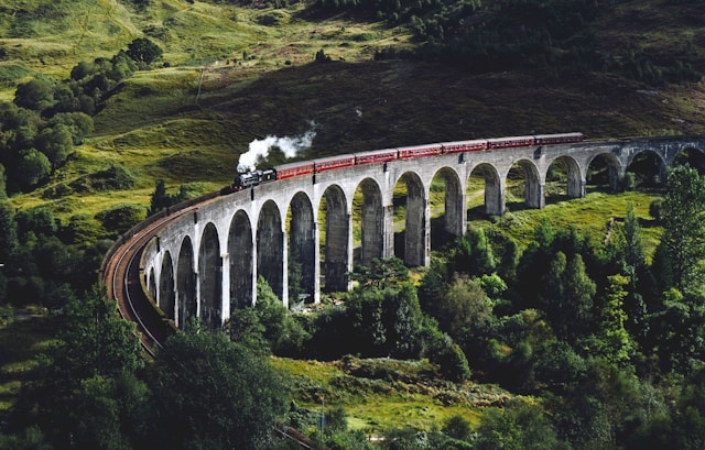 Green landscape, bridge in the middle, steam train chugging along, making steady progress along the bridge.