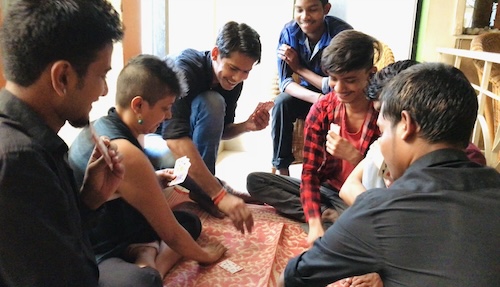 Group of Indian people, Carrots Vegan Restaurant Team, in huddled on the floor playing cards. Playfulness for uplifting energy. Emotional spiral chart.