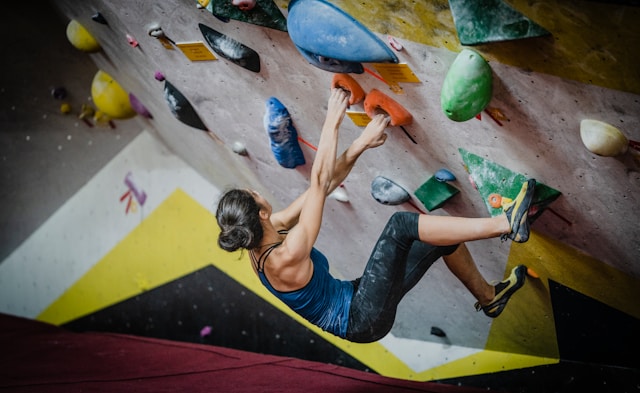 Woman climbing up an indoor rock climbing vertical wall.