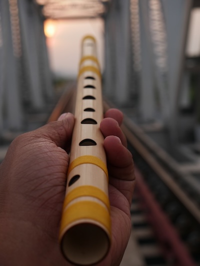 Close up of hand holding a bamboo flute horizontally towards the camera.