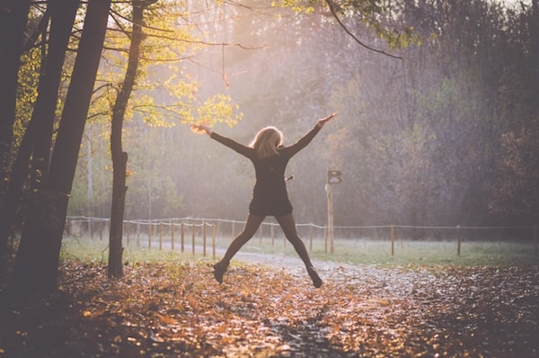 Silhouette of woman jumping up with hands and legs spread wide. Happiness. One small decision can change your life. Go vegan.