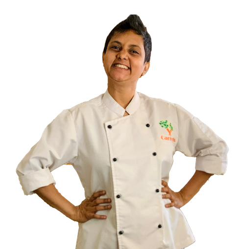 Super short haired Indian girl, hands on hips, smiling wide, wearing a chef coat. Susmitha Veganosaurus.