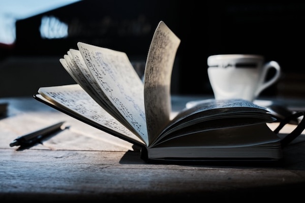 Light and dark photo of notebook book (side view) open on a desk. Simple, clear writing.