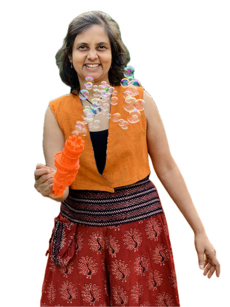 Susmitha, vegan expert coach, smiling and holding a bubbles gun. Happy, laughing, joyful.